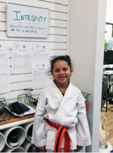 child in Taekwondo clothing with poster celebrating integrity
